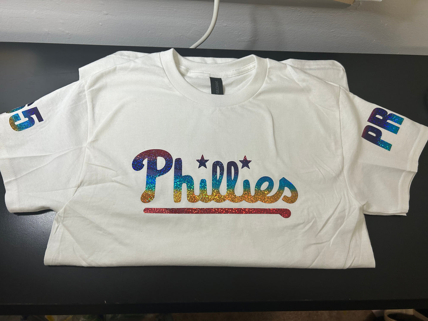 White t-shirt with 'Phillies' logo on a black surface